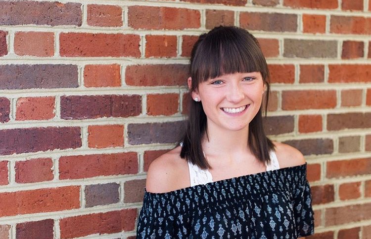 Olivia Brown standing near a brick wall 